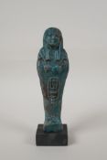 An Egyptian turquoise glazed faience shabti, mounted on a display base, 7" high