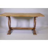 An antique elm refectory table with single plank top, raised on shaped end supports united by a