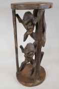 An African hardwood stand, carved as two caged figures, 23½" high