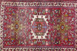 A Persian red ground wool tribal rug with geometric medallion decoration, 26" x 36"