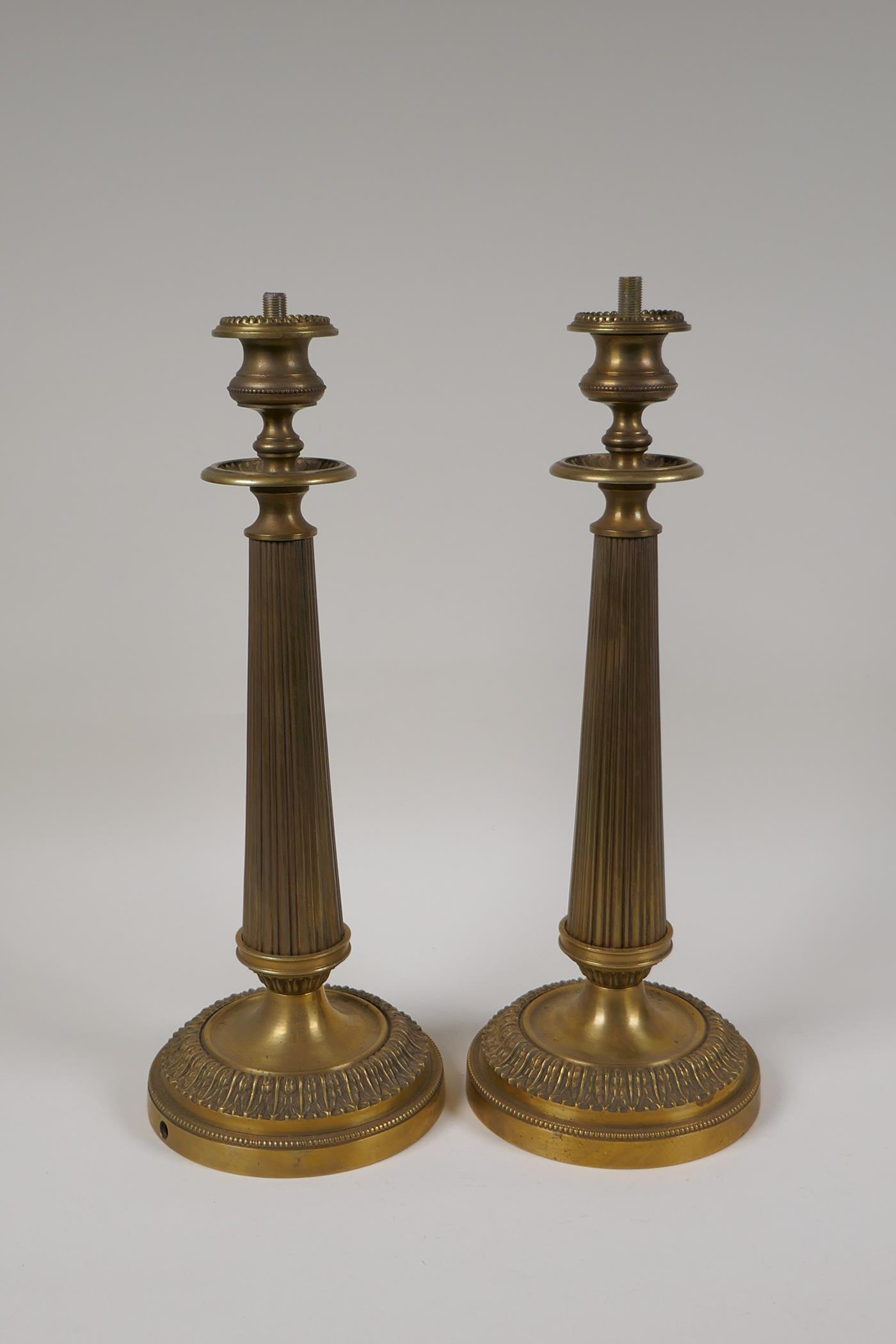 A pair of bronze Empire style candlesticks in the form of fluted columns, part converted for