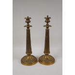 A pair of bronze Empire style candlesticks in the form of fluted columns, part converted for