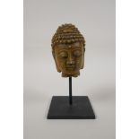 A Chinese reconstituted stone bust of Buddha, on a display mount, 7" high