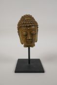 A Chinese reconstituted stone bust of Buddha, on a display mount, 7" high