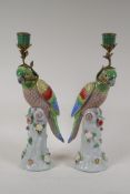 A pair of porcelain parrot candlesticks with brass mounts, decorated in polychrome bright enamels,