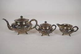 A C19th Chinese three piece silver tea set with embossed dragon decoration, bamboo shaped handles