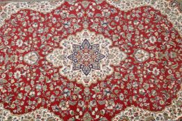 A Belgian red ground Persian style rug with a floral medallion design and blue borders, 90" x 63"