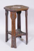 An Arts and Crafts oak two tier jardiniere stand with carved decoration, raised on shaped