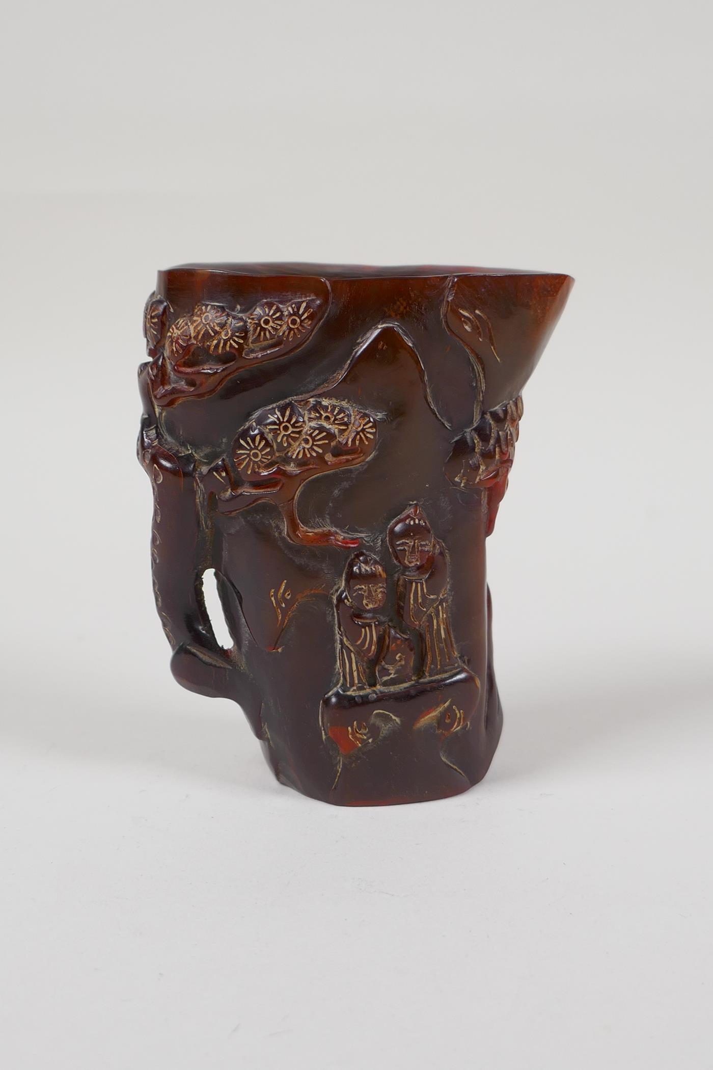 A Chinese carved horn libation cup, decorated with figures beneath trees, inscribed 4 character mark