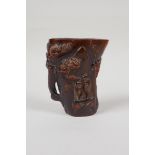 A Chinese carved horn libation cup, decorated with figures beneath trees, inscribed 4 character mark