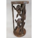 An African hardwood stand, carved as two caged figures, 23½" high