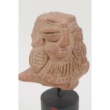 An Eastern terracotta head, 3" long, on turned stand