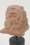 An Eastern terracotta head, 3" long, on turned stand
