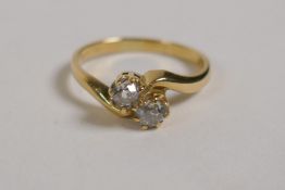 An 18ct yellow gold cross over ring set with two diamonds, approx 48 points, size K