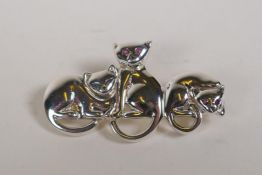 A sterling silver brooch in the form of three cats with ruby set eyes, 1½" long