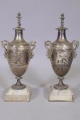 A pair of silver plated urns with raised classical decoration and satyr mask handles, raised on