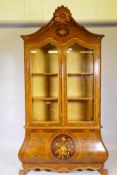 A continental bombe shaped burr walnut display cabinet, the upper section with two glazed doors, the