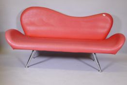 A 1960s style red leatherette shaped back settee on chrome supports, 72" long