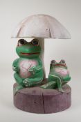 An African carved and painted wood ornament in the form of two frogs beneath a mushroom, 15" high