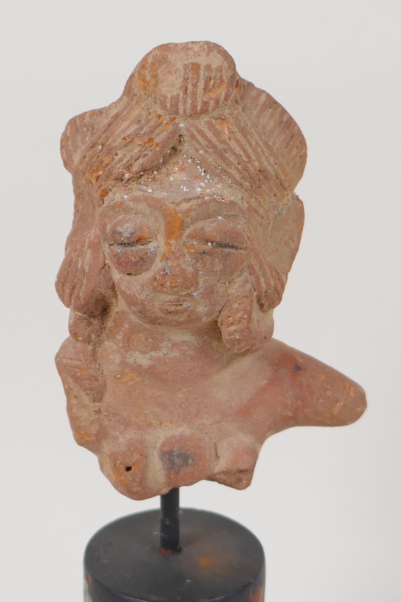 An Eastern terracotta head, 3" long, on turned stand