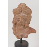An Eastern terracotta head, 3" long, on turned stand