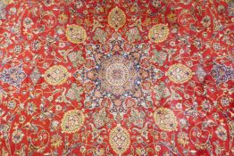 A Belgian red ground wool Persian style carpet with a central floral medallion design and blue