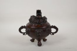 A Chinese bronze two handled censer and cover on tripod supports, with raised dragon and flaming