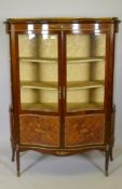 A French marquetry inlaid mahogany serpentine front vitrine with brass mounts, the interior with