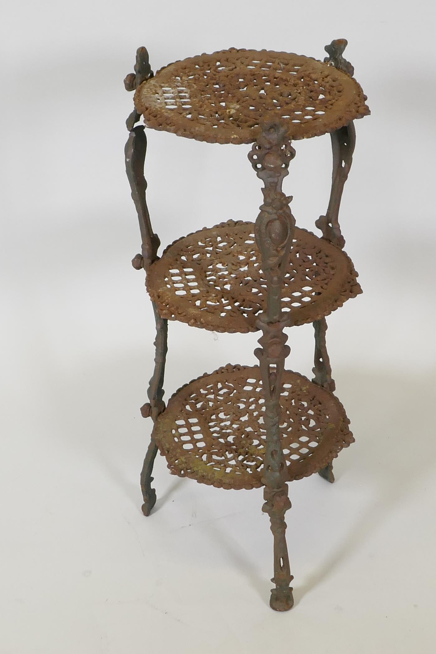 A cast iron three tier garden pot stand on cast supports, 26" high, AF