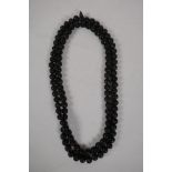 A string of Chinese black lacquer beads with carved auspicious symbol decoration, 51" long
