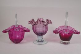 A pair of cranberry glass flower baskets with frilled rims, and a similar vase, largest 9" high