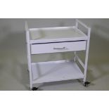 A metal trolley with tray top, single drawer and undertier, raised on braked castors, 24" x 16" x