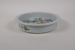 A famille vert porcelain steep sided dish decorated with figures travelling in a landscape,