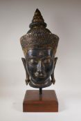A Thai gilt bronze Buddha head, on a hardwood display stand, 27" high