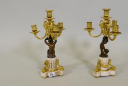 A pair of bronze and ormolu candelabra, the three branches with ram's mask decoration, supported