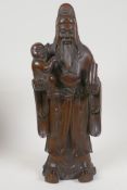 A Chinese rootwood carving of the Immortal Guanghong carrying a child, 12" high