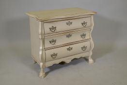 A small painted bombe shaped commode of three drawers, with shaped top, raised on paw feet, 30" x