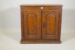 A C19th French fruitwood cupboard, two doors with shaped fielded panels, raised on a plinth base,