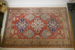 An antique oriental wool rug with blue medallion design on a terracotta field