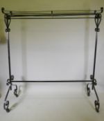 A painted wrought metal shop clothes rack, on castors, 71" wide, 80" high