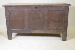 An C18th oak coffer with triple panel front and carved decoration, raised on stile supports, 54" x