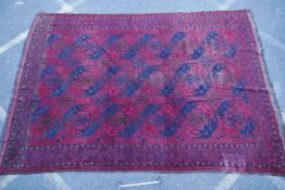 An antique Turkish Bokhara carpet with geometric designs on a red ground