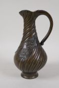 An Art Nouveau bronze jug, decorated with a raised floral design, 9" high