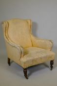 A Victorian wing back easy chair, raised on turned supports with brass and ceramic castors