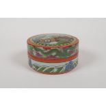A famille vert porcelain cylinder box and cover, decorated with a landscape scene, dragons and the