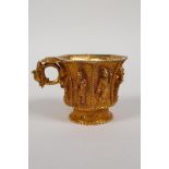 A Chinese gilt metal libation cup of octagonal form, the eight sides with raised figural decoration,