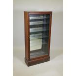 A Victorian walnut shop display cabinet, with single glazed door, mirror back and glass shelves,