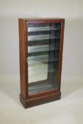 A Victorian walnut shop display cabinet, with single glazed door, mirror back and glass shelves,