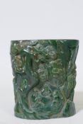 A Chinese green glass brush pot, with raised decoration of gentlemen seated under cypress trees,