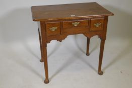 A Georgian oak lowboy, with three drawers, raised on turned tapering supports with pad feet, 31" x